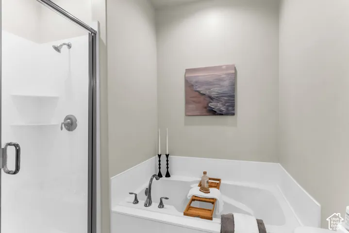 Walk-in shower with a glass enclosure and a built-in soaking tub featuring a deck-mounted faucet