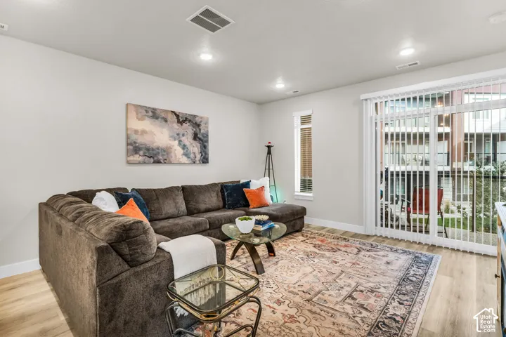 Neutral-toned interior featuring wood-finish flooring, recessed lighting, and sliding glass doors with vertical blinds