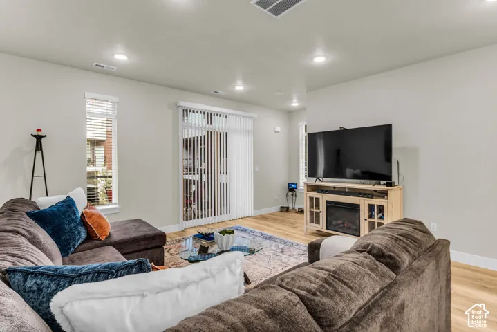 Living area featuring wood-finish flooring, recessed lighting, and vertical blinds covering the sliding glass door