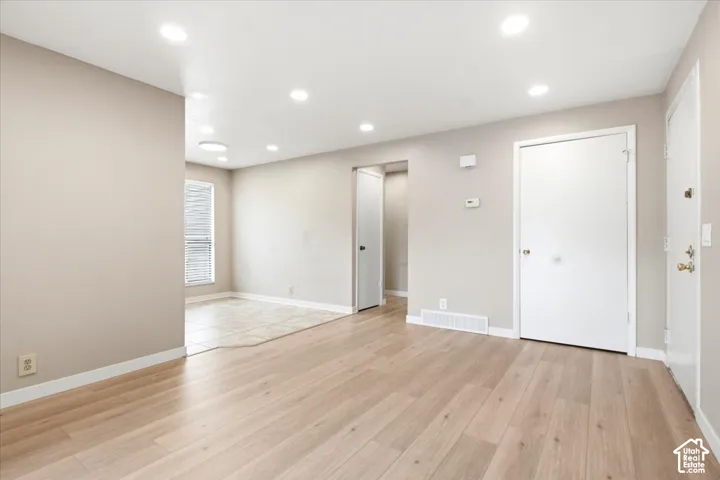 Interior space featuring neutral wall paint, recessed lighting, wood-finish flooring, tile flooring, and a window with blinds