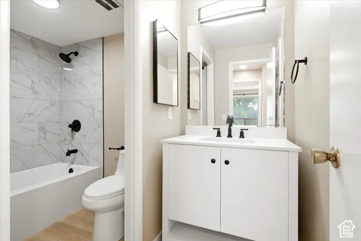 Bathroom featuring a white vanity cabinet with a stone-surface countertop, matte black fixtures, full-length mirror, and shower-tub combination with patterned tile surround