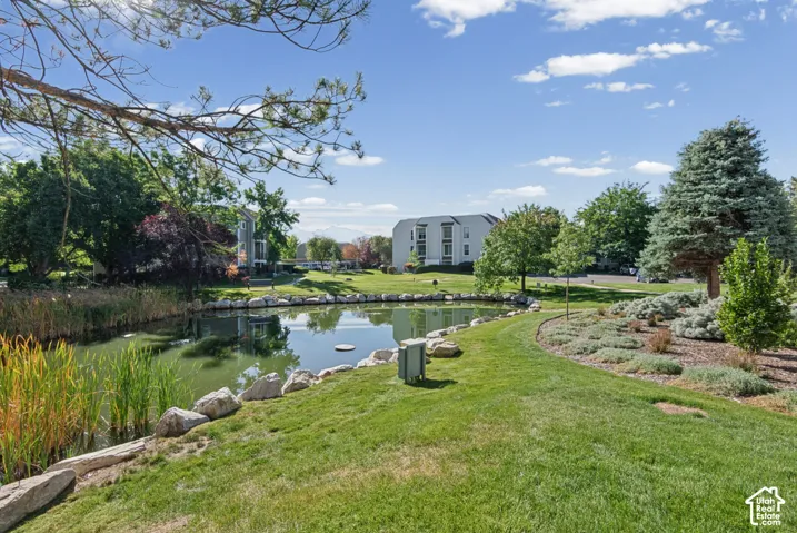 Scenic pond featuring rock-lined banks, surrounded by manicured turf, mature landscaping, and native shrubbery