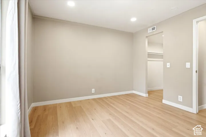 Interior room featuring wood-finish flooring, neutral wall paint, recessed lighting, and a walk-in closet with built-in shelving
