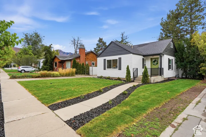 Exterior featuring a painted brick facade, dark horizontal siding, asphalt shingle roof, and a front walkway bordered by decorative rock landscaping