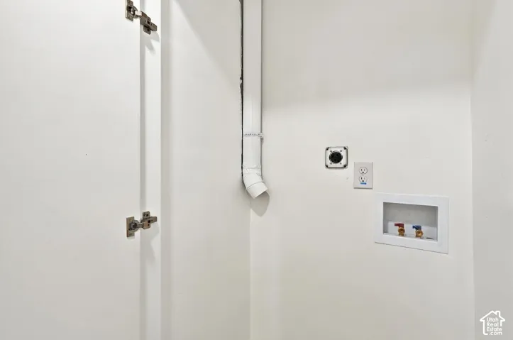 Utility area featuring a recessed water connection box, dedicated electrical outlet, and integrated dryer exhaust vent