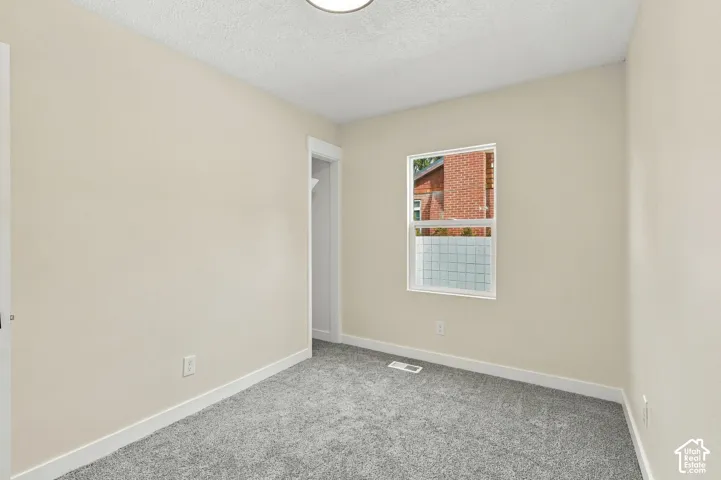 Neutral-toned walls, grey carpet flooring, white trim, and a single-pane window