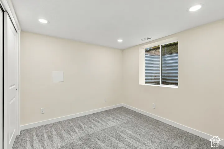 Neutral-toned room featuring grey wall-to-wall carpeting, recessed ceiling lighting, and a sliding door closet