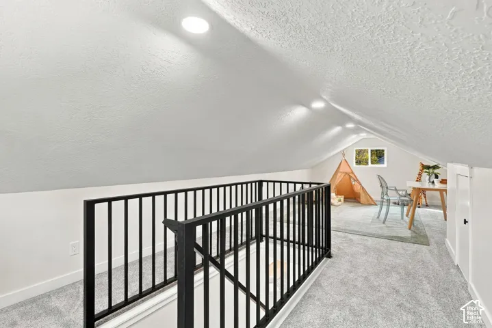 Loft space with with recessed lighting, matte black metal railing, and neutral wall-to-wall carpeting