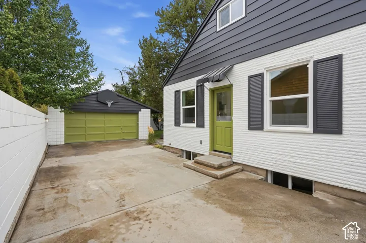 Exterior featuring white painted brick masonry, charcoal-toned horizontal siding, a detached garage, and a concrete driveway
