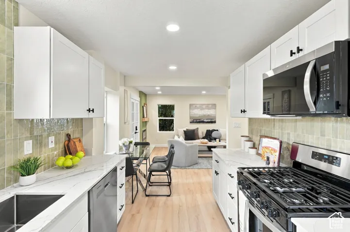 Kitchen featuring white shaker cabinetry, stone-patterned countertops, stainless steel appliances, and a tiled backsplash, complemented by wood-finish flooring