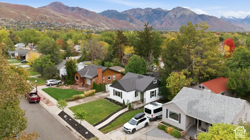Aerial perspective featuring a residential neighborhood with mountain backdrops and mature canopy trees