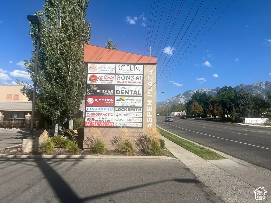Freestanding multi-tenant signage structure with integrated lighting, finished in masonry and metal paneling, situated on a corner lot with mountain scenery