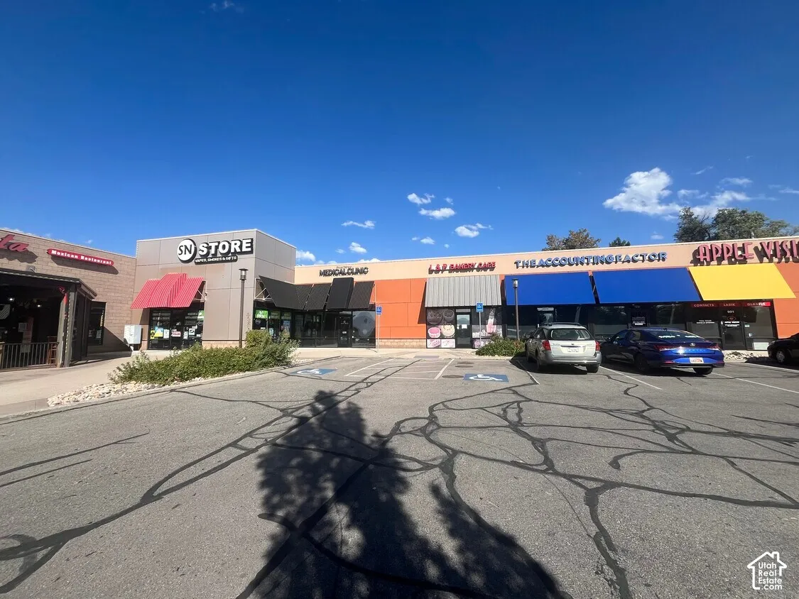 Commercial retail center featuring a multi-tenant facade, asphalt parking lot, designated accessible parking spaces, and colorful exterior awnings
