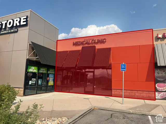 Commercial storefront featuring a red panel facade, brick masonry base, multiple metal awnings, and large glass entry doors