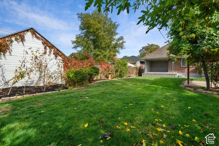 Backyard featuring a manicured lawn, masonry garden borders, a detached garage with siding, and a covered concrete patio