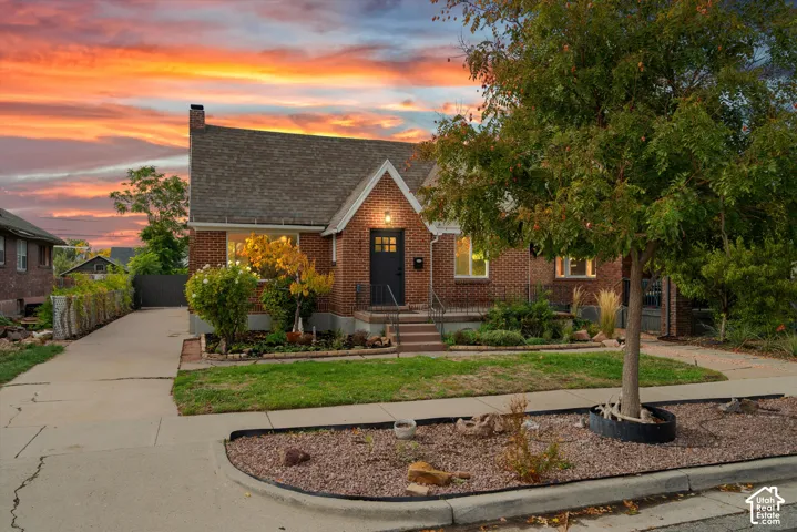 Brick exterior residence featuring a steeply pitched roofline, prominent front-facing gable, concrete driveway, and established landscape