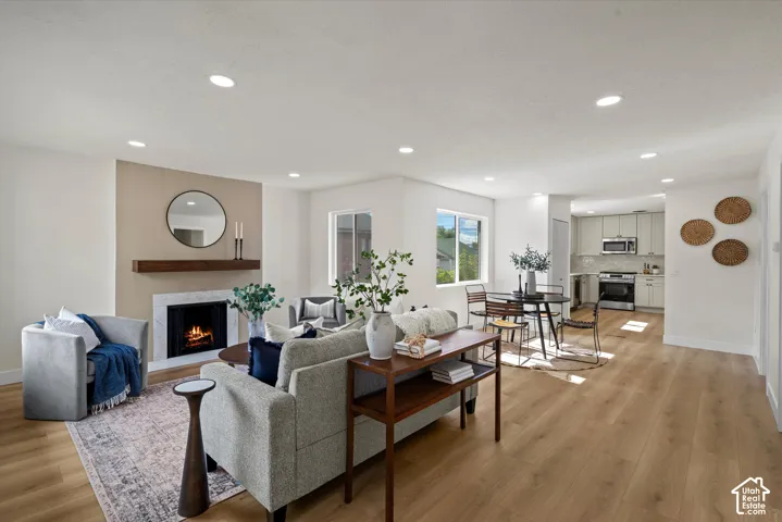 Living area featuring wood-finish flooring, recessed lighting, and a fireplace with a stone-surround mantle