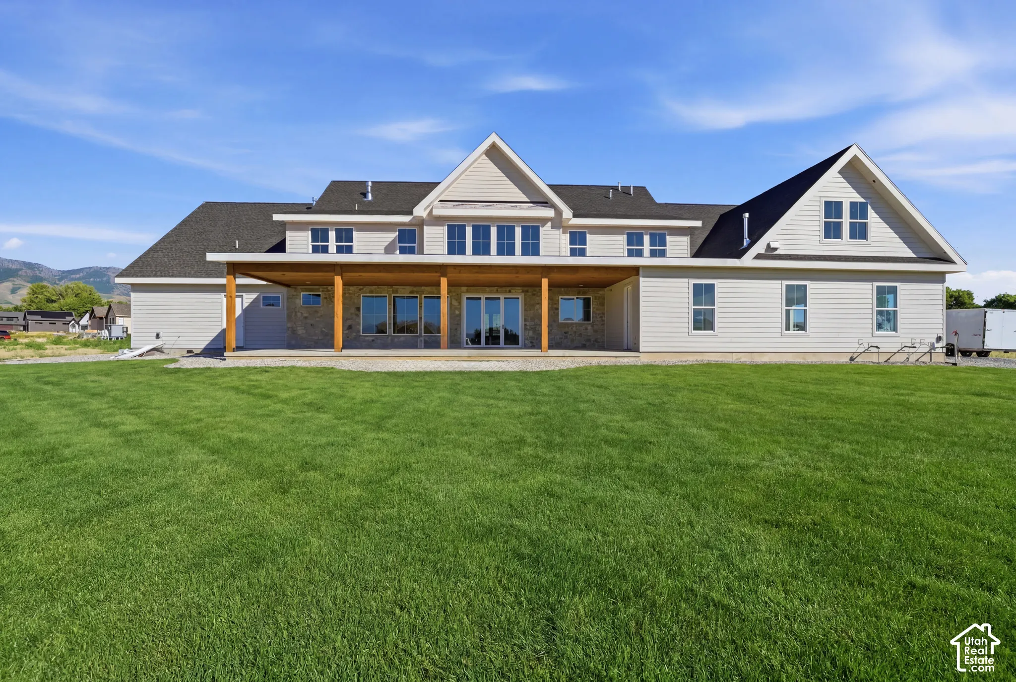 Exterior features include horizontal lap siding, a covered patio with wooden support posts, stone-veneer accents, and a multi-gabled roofline