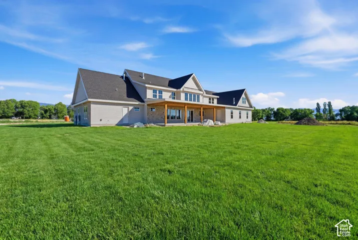 Expansive rear grounds featuring a multi-gabled roofline, stone veneer siding, and a covered timber-framed porch