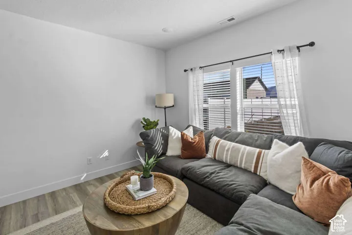 Neutral-toned interior space featuring wood-finish flooring and dual windows with black curtain hardware