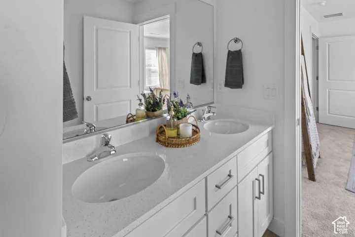Dual-vanity bathroom featuring a white composite countertop, undermount sinks, chrome fixtures, and white shaker-style cabinetry
