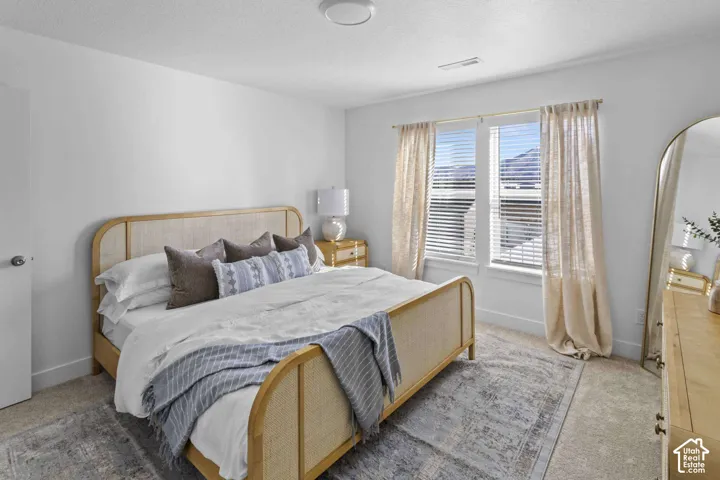 Neutral wall paint, plush carpeting, and two tall windows with horizontal blinds