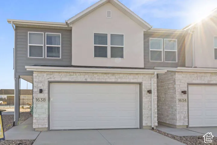 Multi-level exterior featuring a stone veneer lower facade, horizontal siding, two-car garage, and double-pane windows