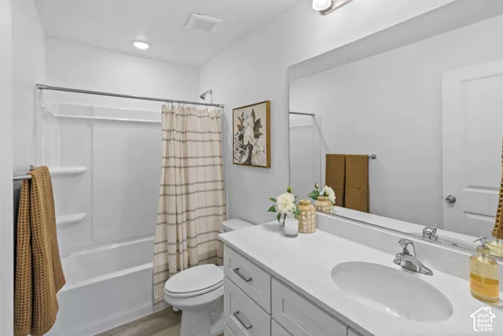 Bathroom featuring a vanity with a white countertop, undermount sink, brushed-nickel hardware, large wall-mounted mirror, and a tub-shower combination with integrated shelving