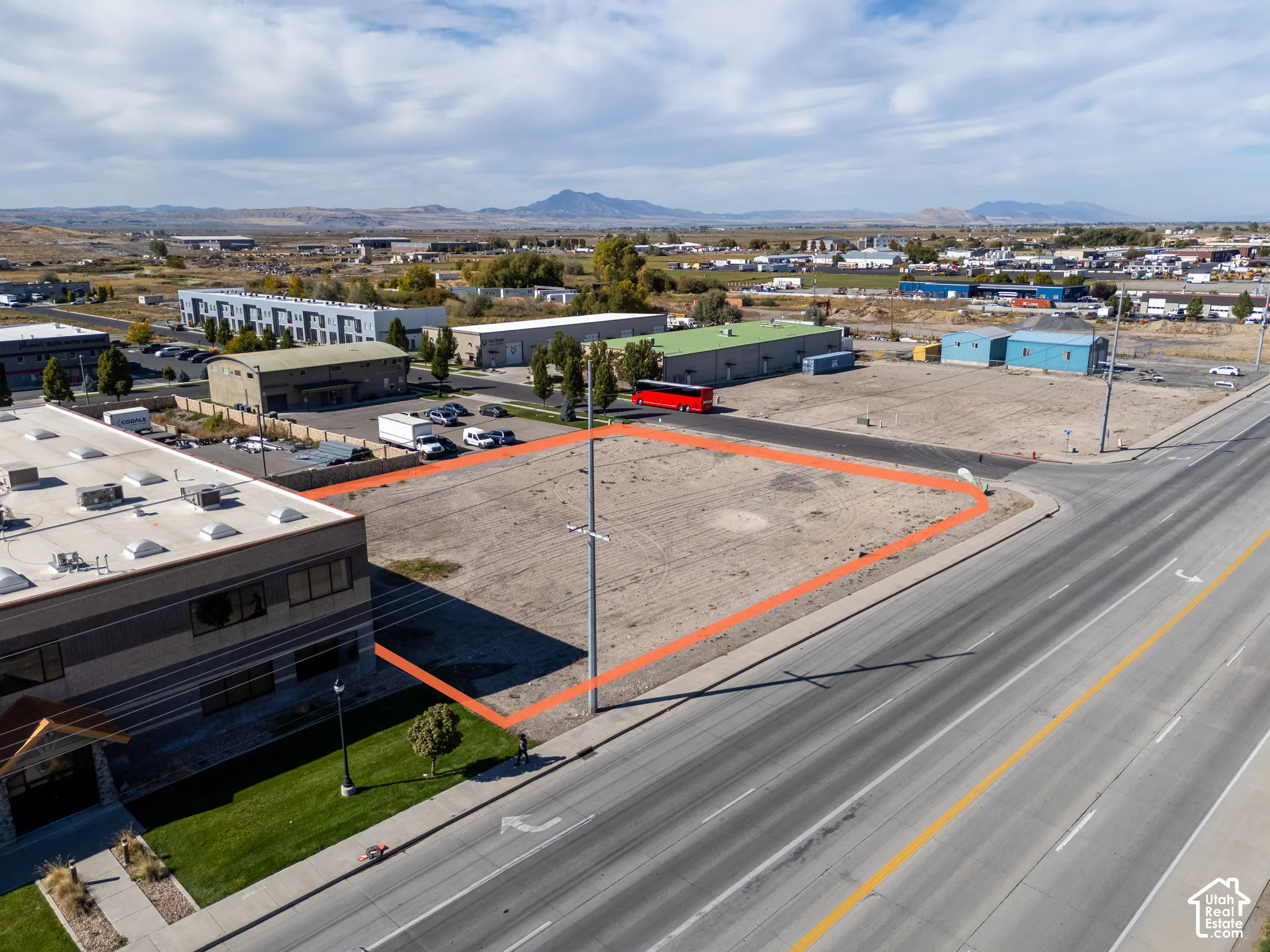 Corner commercial lot featuring high-visibility road frontage, level topography, and prominent mountain backdrops