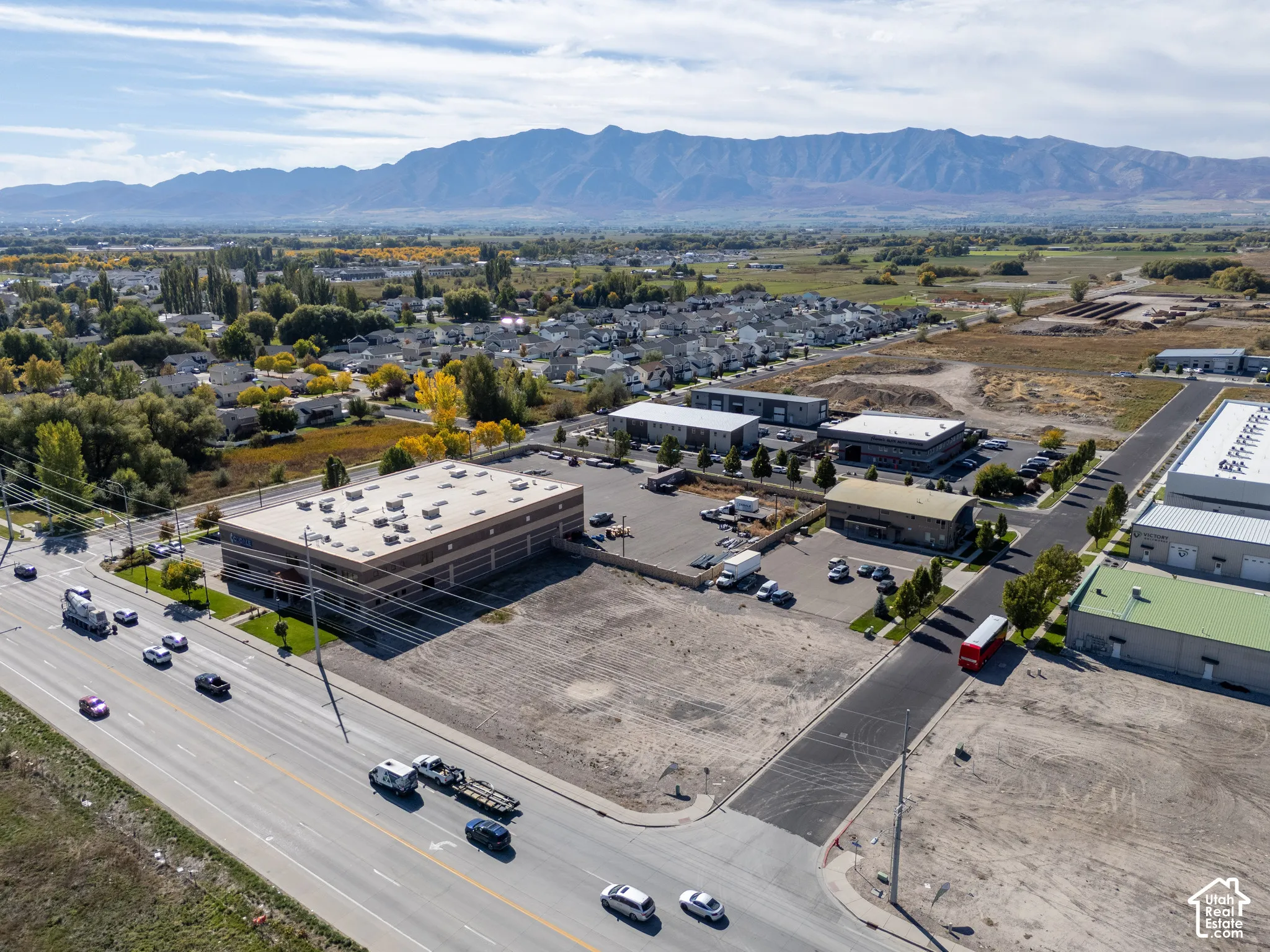 Commercial property featuring a multi-story building, paved parking surface, and mountain backdrop