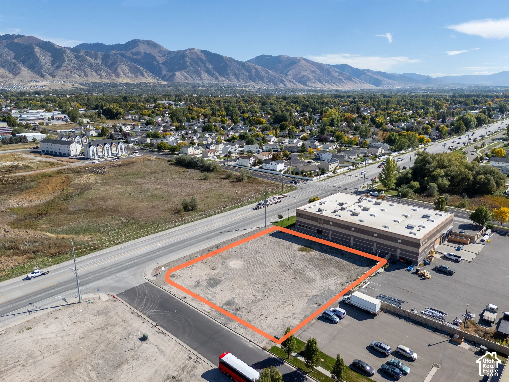 Cleared commercial land parcel featuring paved street frontage and prominent mountain backdrops