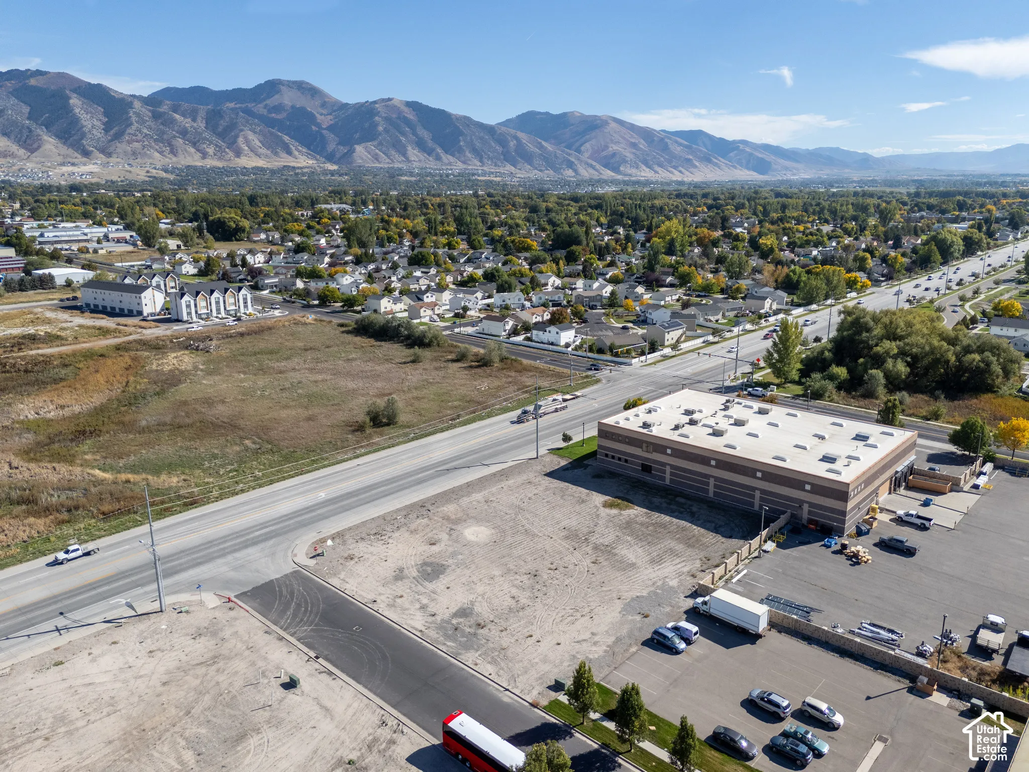 Aerial perspective of a vacant lot featuring paved street access and mountain backdrops