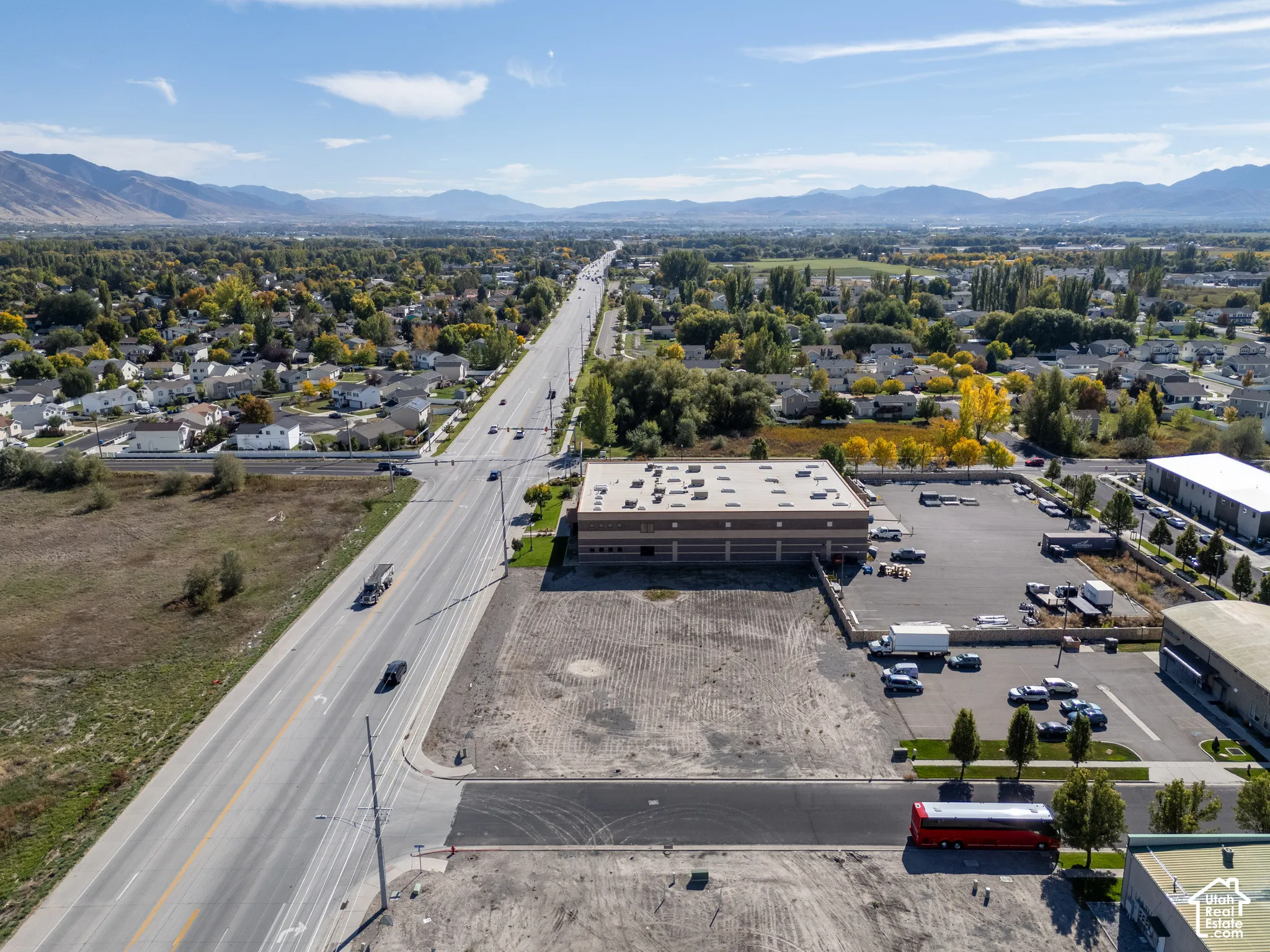 Commercial property featuring paved parking area, masonry building construction, and direct access to a multi-lane thoroughfare with mountain surroundings