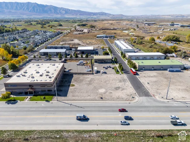 Industrial property complex featuring multiple multi-unit warehouses, a large detached office building, expansive asphalt parking areas, and prominent mountain backdrops