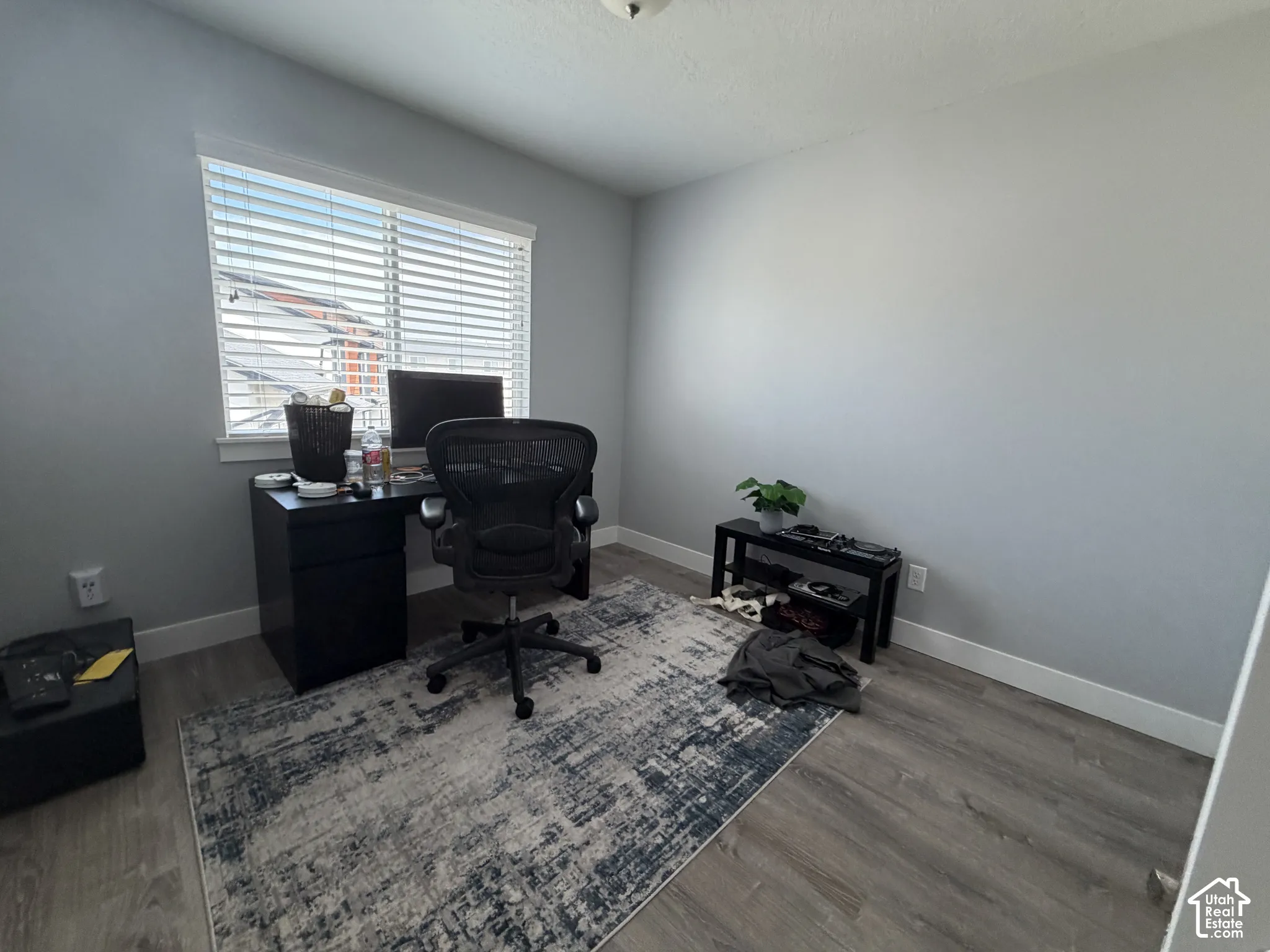 Room featuring wood-finish flooring, neutral wall paint, and a window with horizontal blinds