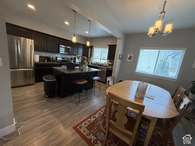 Kitchen featuring dark cabinetry, stone-surface central island, stainless steel appliances, recessed lighting, and wood-finish flooring