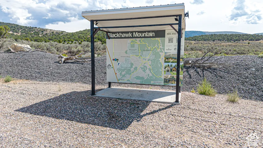 Permanent information kiosk featuring a metal roof structure, steel support beams, and a concrete base, set within a gravel-surfaced lot