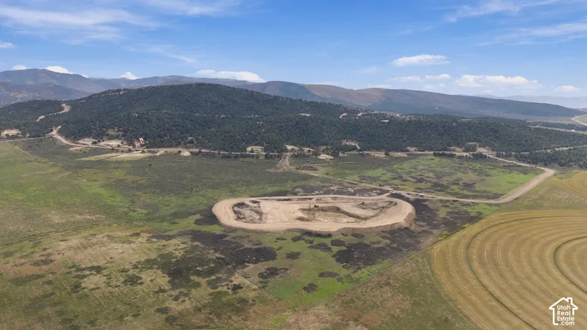Expansive parcel of land featuring mountain topography, native vegetation, and a cleared building site