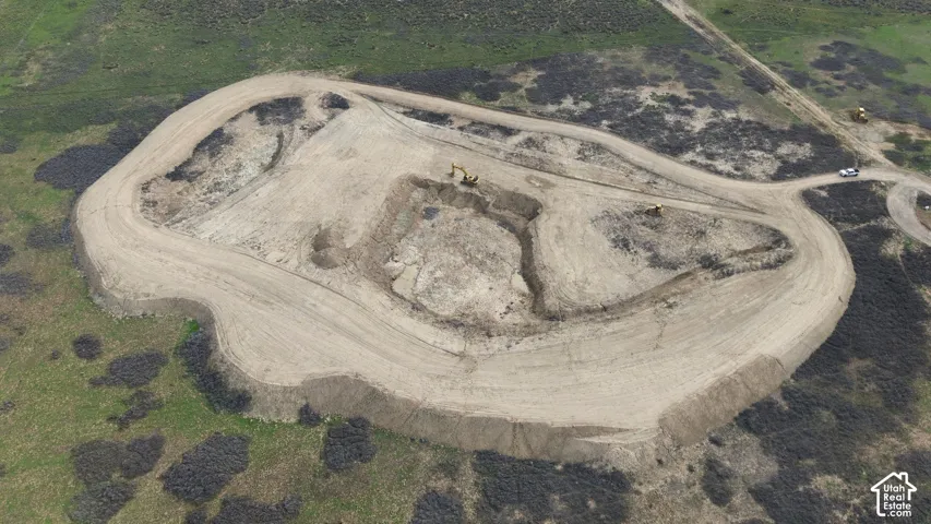 Expansive parcel of land featuring graded earthwork, cleared building site, and perimeter access paths