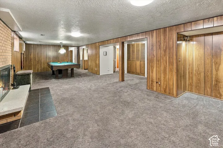 Wood-paneled interior walls, masonry fireplace with a tile hearth, carpeted flooring, and built-in closet storage