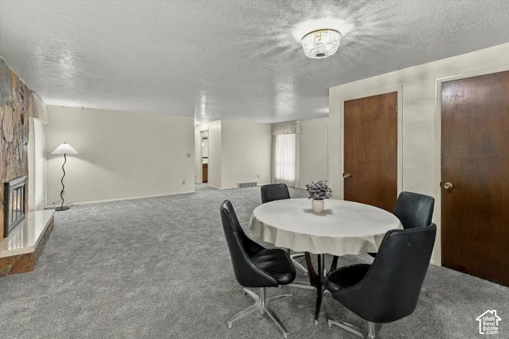 Living area featuring floor-to-ceiling stone fireplace, raised hearth, carpeted flooring, flush-mount lighting, and solid core wood doors
