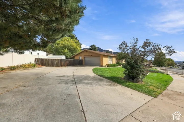 Single-story residence featuring a two-car garage, expansive concrete driveway, and established landscaping