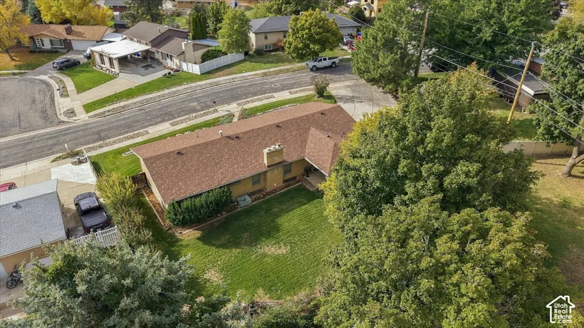 Single-story residence featuring an asphalt shingle roof, masonry chimney, and private lawn with mature trees