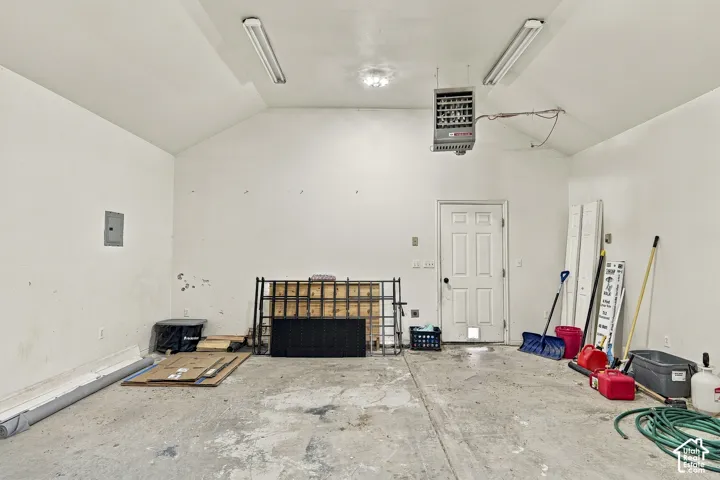 Garage space featuring vaulted ceilings, dual overhead fluorescent lighting, and a ceiling-mounted utility heater