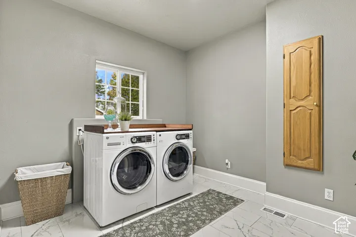 Laundry space featuring stone-style tile flooring, built-in wooden cabinetry, and a window with divided-lite muntins