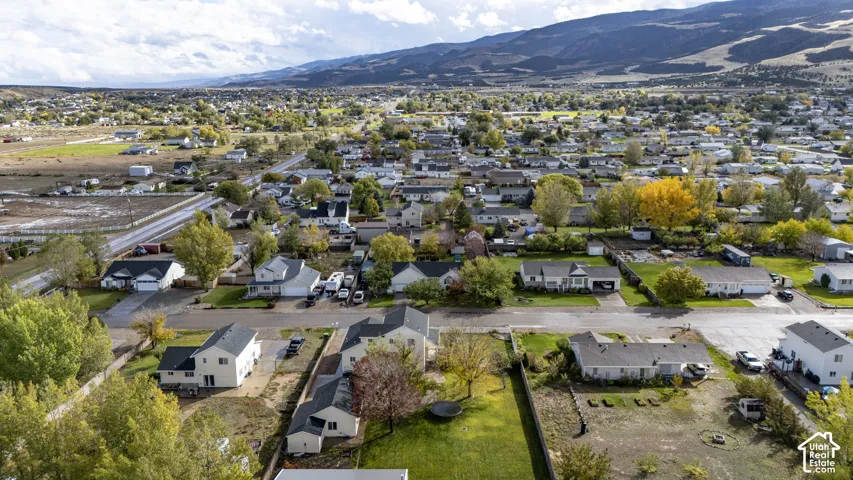 Aerial perspective of the residential area featuring established mature trees, expansive mountain backdrop, and grid-patterned streets