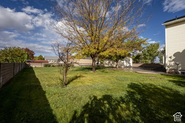 Expansive backyard featuring a lawn, stone patio, masonry perimeter wall, and mature trees