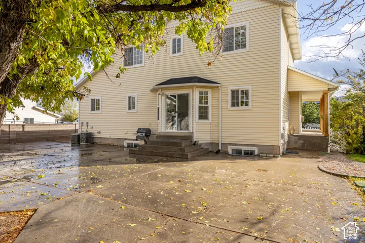 Two-story exterior featuring light-colored horizontal siding, a rear concrete patio, sliding glass door, and an attached side porch with wood-post support