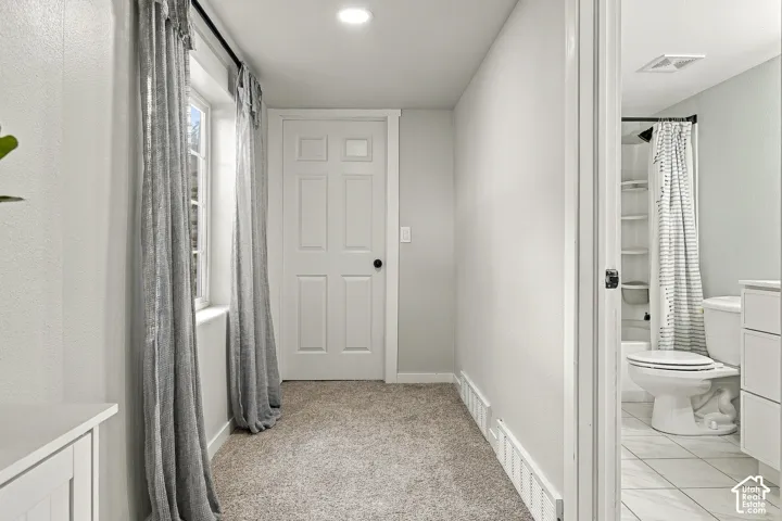 Neutral-toned carpet, paneled interior door with black hardware, and crisp white trim