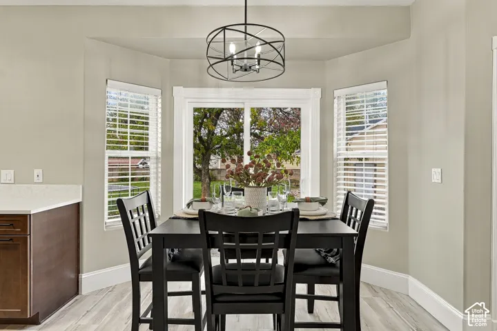 Dining area featuring a bay window, sliding glass door, modern geometric metal chandelier, and wood-finish flooring